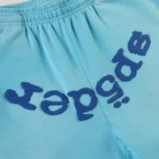Close-up view of the Sp5der OG Web V2 Spray Light Blue sweatpant featuring signature puff print brand detailing.