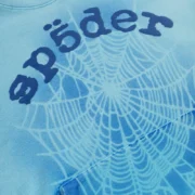 Detailed close-up view of the Sp5der OG Web V2 Spray Tracksuit in light blue featuring the signature puff print web logo.