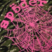 Close-up view of the Sp5der OG Web V2 Tiger Camo hoodie featuring a bold pink puff print web graphic on green camo.
