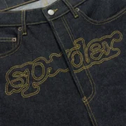 Close-up view of the Sp5der Punk V3 Indigo Denim jeans featuring bold signature embroidered logo on the crotch area.