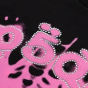 Close-up of the Sp5der Scattered OG Web V2 Tee featuring iconic pink graphic print embellished with rhinestone details.