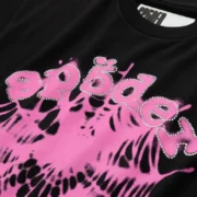 Close-up of Sp5der Scattered OG Web V2 black t-shirt featuring pink graphic branding with sparkling rhinestone detail.