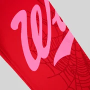 Close-up view of Sp5der Stadium sweatpants in red, featuring signature pink Wait script and intricate web graphic print.