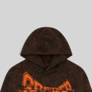 Close-up of the Sp5der T&F Tree Camo Hoodie in brown, featuring signature orange graphic text on 100% cotton fleece.