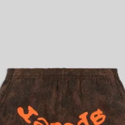Close-up detail of Sp5der T&F Tree Camo sweatpants in brown featuring a signature orange graphic print on front.