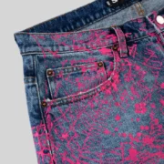Close up view of the Sp5der V2 Web Denim Indigo jeans featuring an all over bright pink web print and metal hardware.