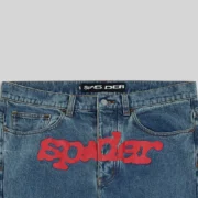 Close-up view of the Sp5der V3 Light Wash Indigo Denim featuring iconic red brand graphic print on the front crotch area.