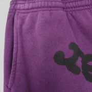 Close-up view of the purple Sp5der Web V2 sweatpants showing the signature heavyweight cotton fleece fabric texture.