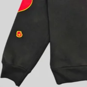 Close-up view of the black Sp5der x UY Scuti hoodie sleeve showing the red graphic design and premium cotton texture.