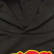 Detailed close-up view of the black cotton fabric and collar construction on the collaborative Sp5der x UY Scuti Hoodie.